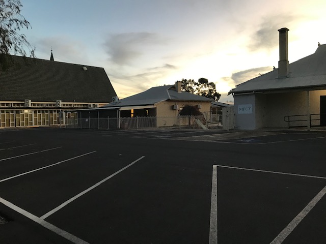 Photograph of carpark behind a church and buildings in the twilight