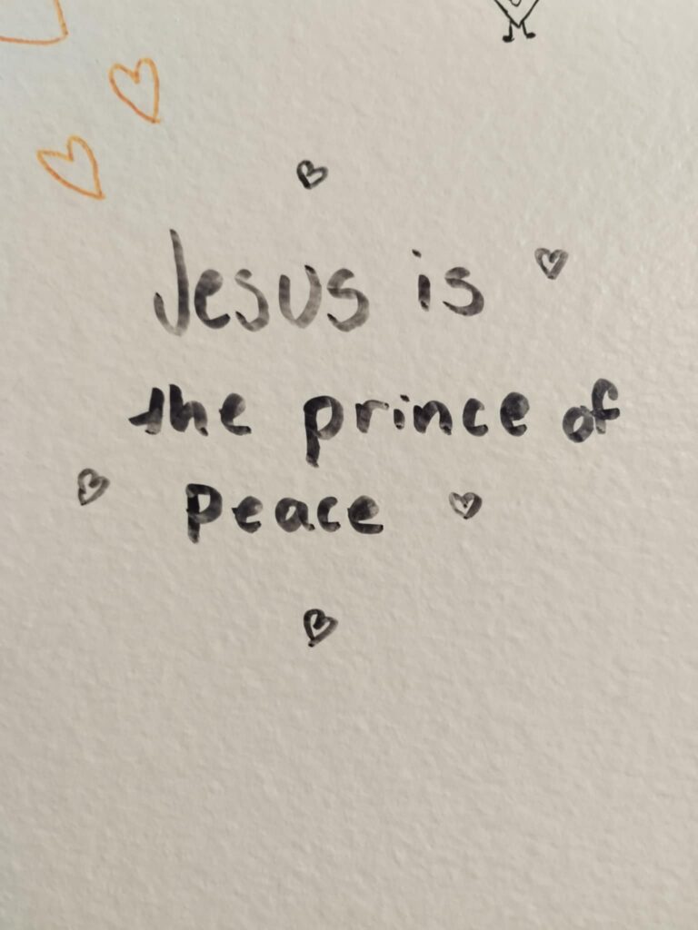 Graffiti on a surface saying "Jesus is the prince of peace" surrounded by hand-drawn love hearts